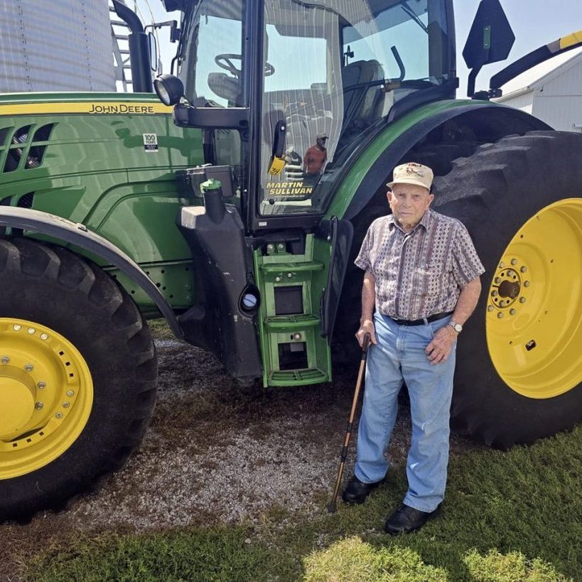 Donnie Peterson poses with his 2018 John Deere 6155 tractor before it sold at a farm equipment auction Aug. 27. (Photo courtesy of Jim Taylor of RFD Radio Network) 