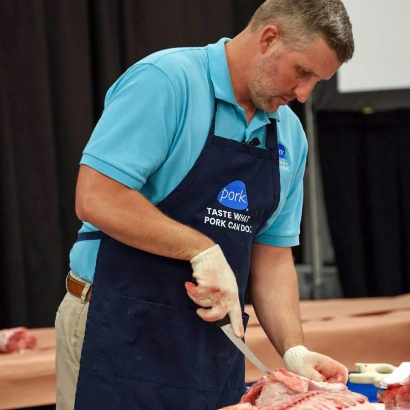 David Newman, National Pork Board CEO, demonstrates how to trim a pork carcass into different cuts this month at the World Pork Expo in Des Moines. (Photo by Rhiannon Branch of FarmWeek) 